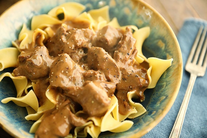 Slow Cooker Beef Stroganoff in a bowl over noodles.