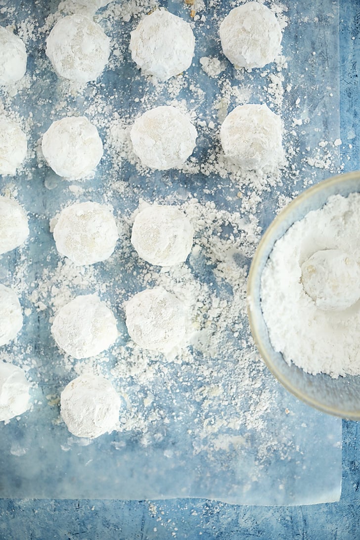 Overhead view of Pecan Snowball Cookies being coated in powdered sugar.