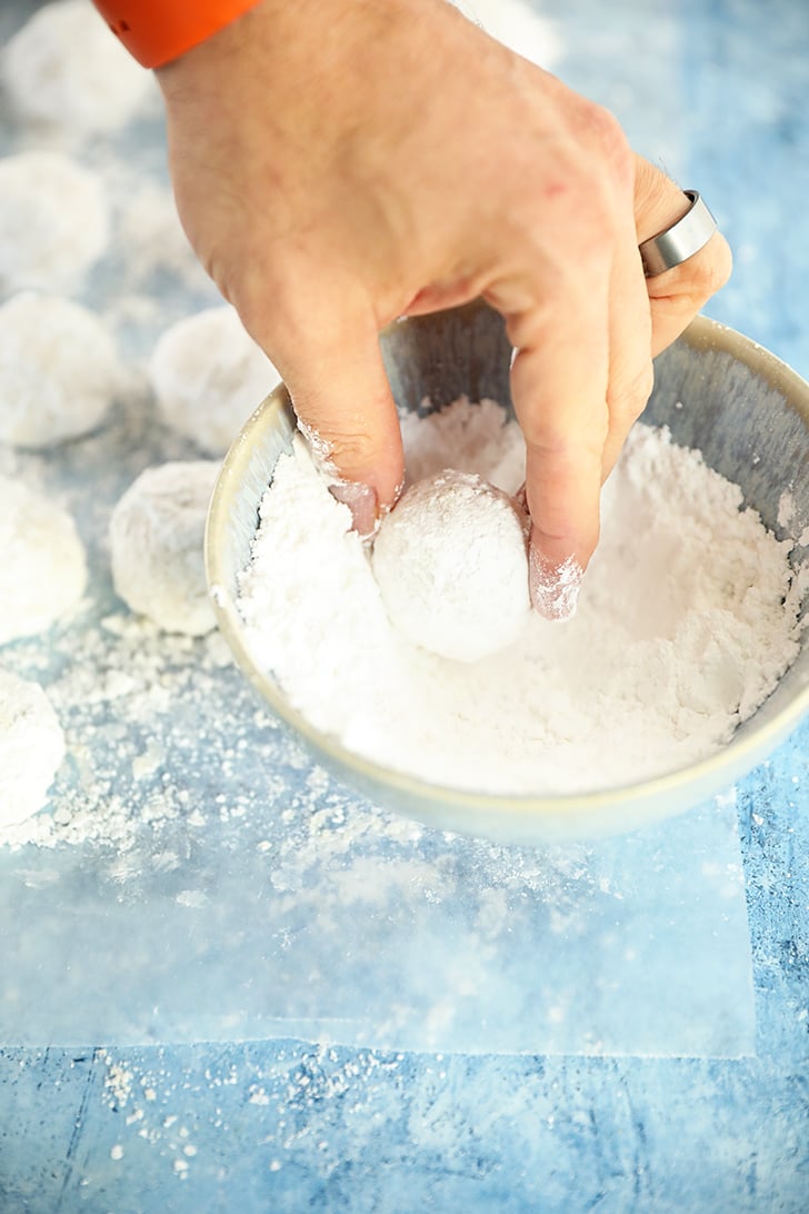 Rolling a Pecan Snowball Cookie in powdered sugar.