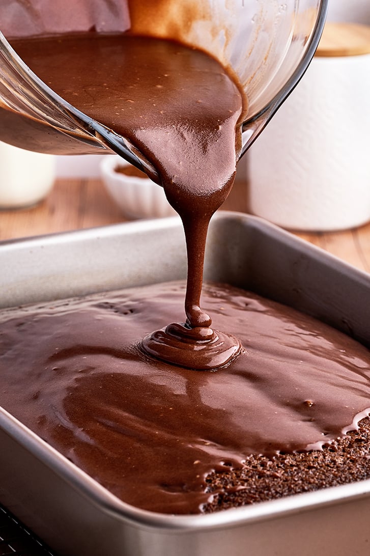 Pouring frosting on Buttermilk Chocolate Cake.