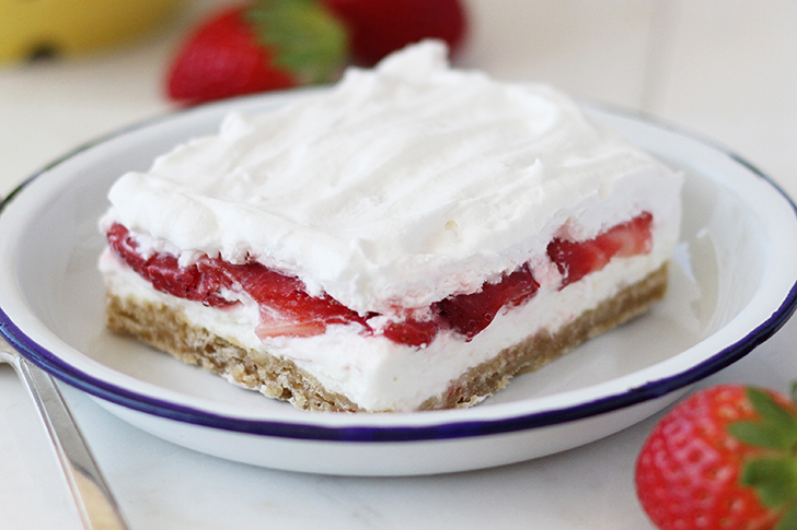 Slice of Strawberry Delight on plate with blue rim.