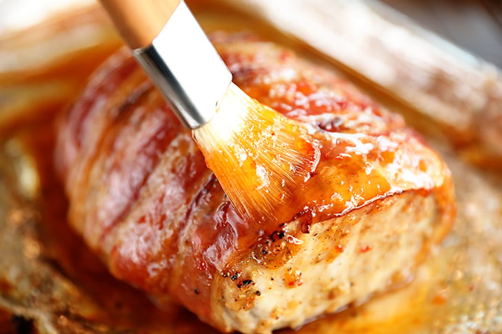 Brushing pepper jelly glaze on pork loin.