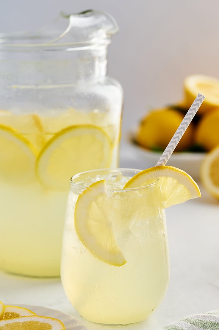 Lemonade in glass with pitcher in the background.