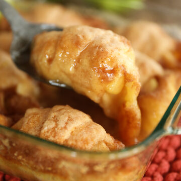 Scooping apple dumpling out of dish.