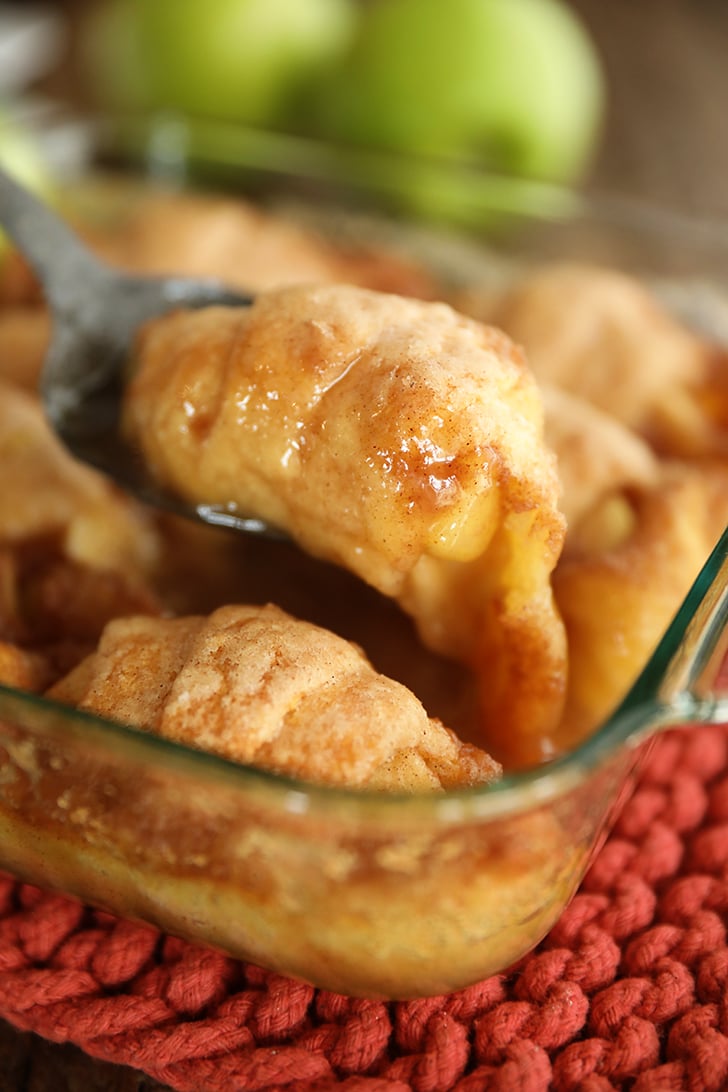 Scooping apple dumpling out of dish.