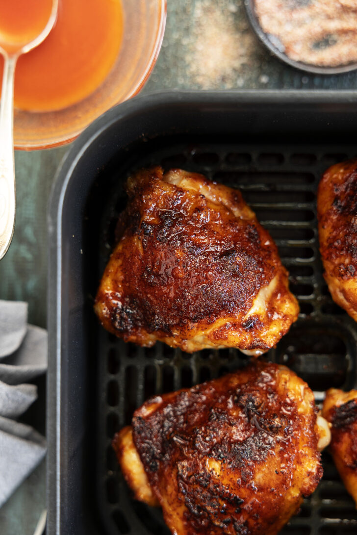 Chicken thighs in an air fryer with hot honey glaze.