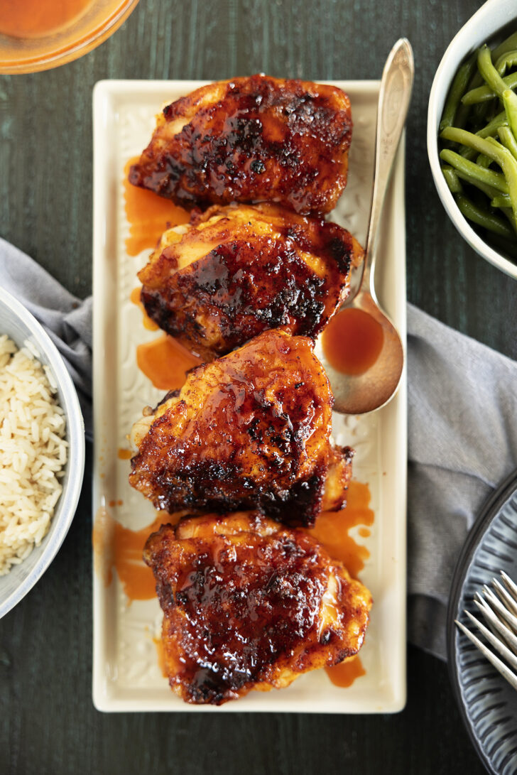 Chicken thighs on a platter with hot honey glaze.