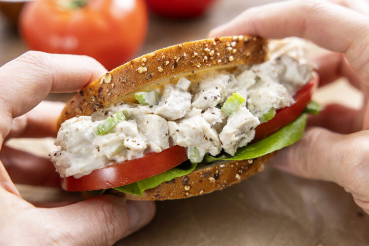 Hands holding a chicken salad sandwich.